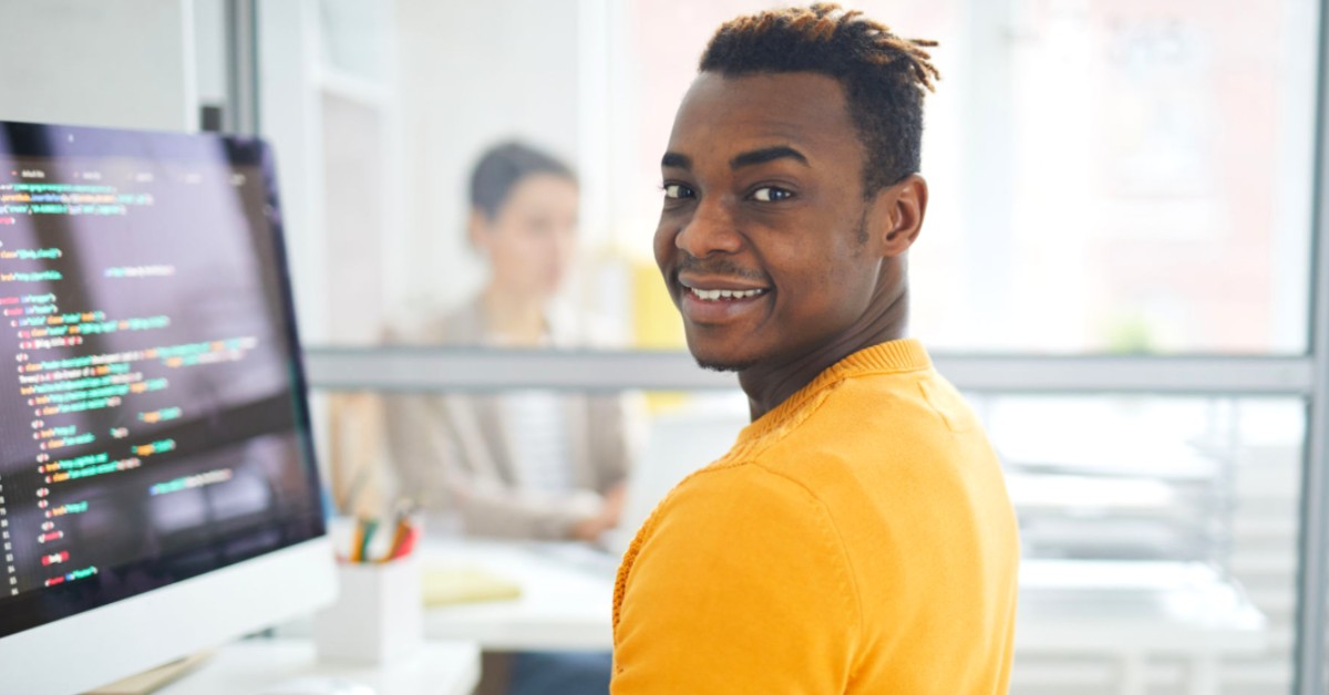 Guy Coding at computer with yellow shirt in an office