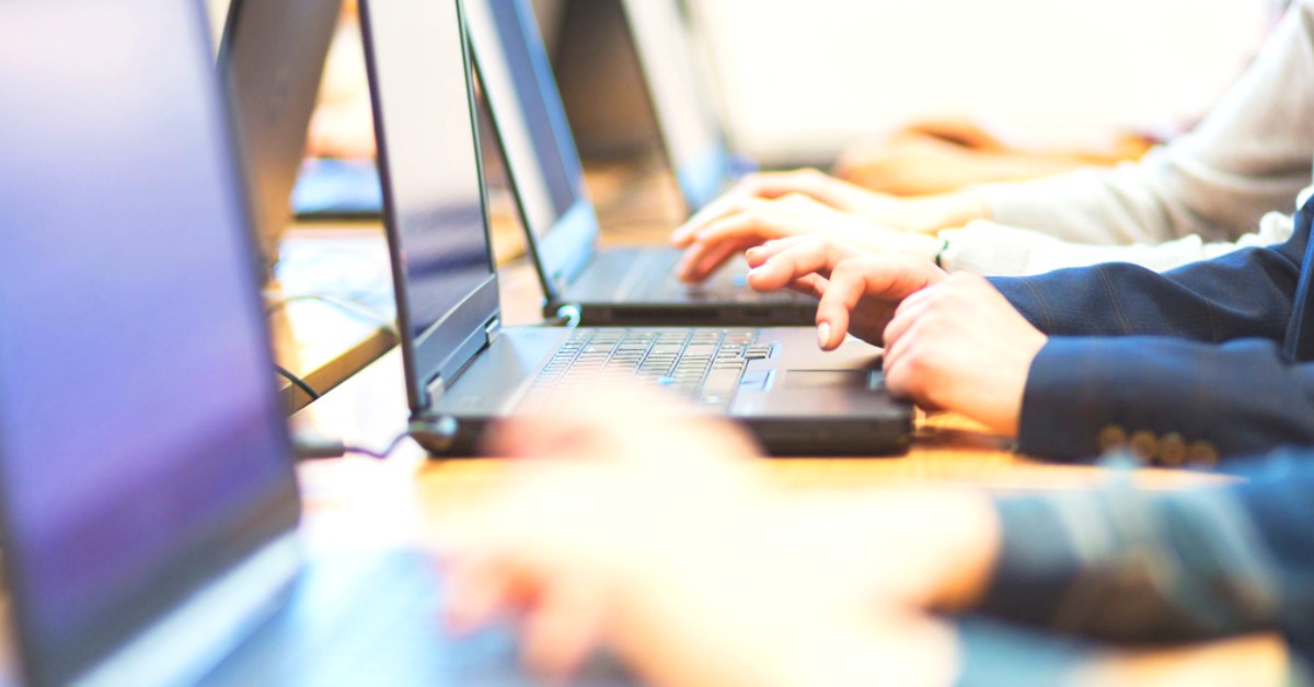 Multiple laptops, hands working and coding