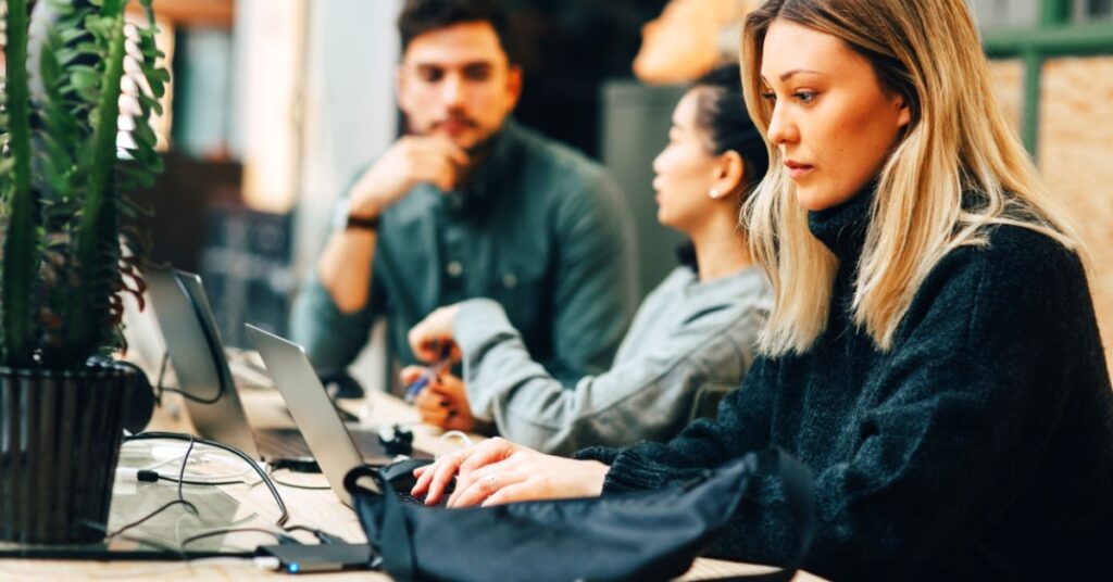 Women working on laptop, people in the background blurred